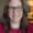 Smiling headshot of a Caucasian woman with brown, straight hair and glasses wearing a maroon top