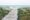 Wooden boardwalk between grass and sand hills leading to blue ocean