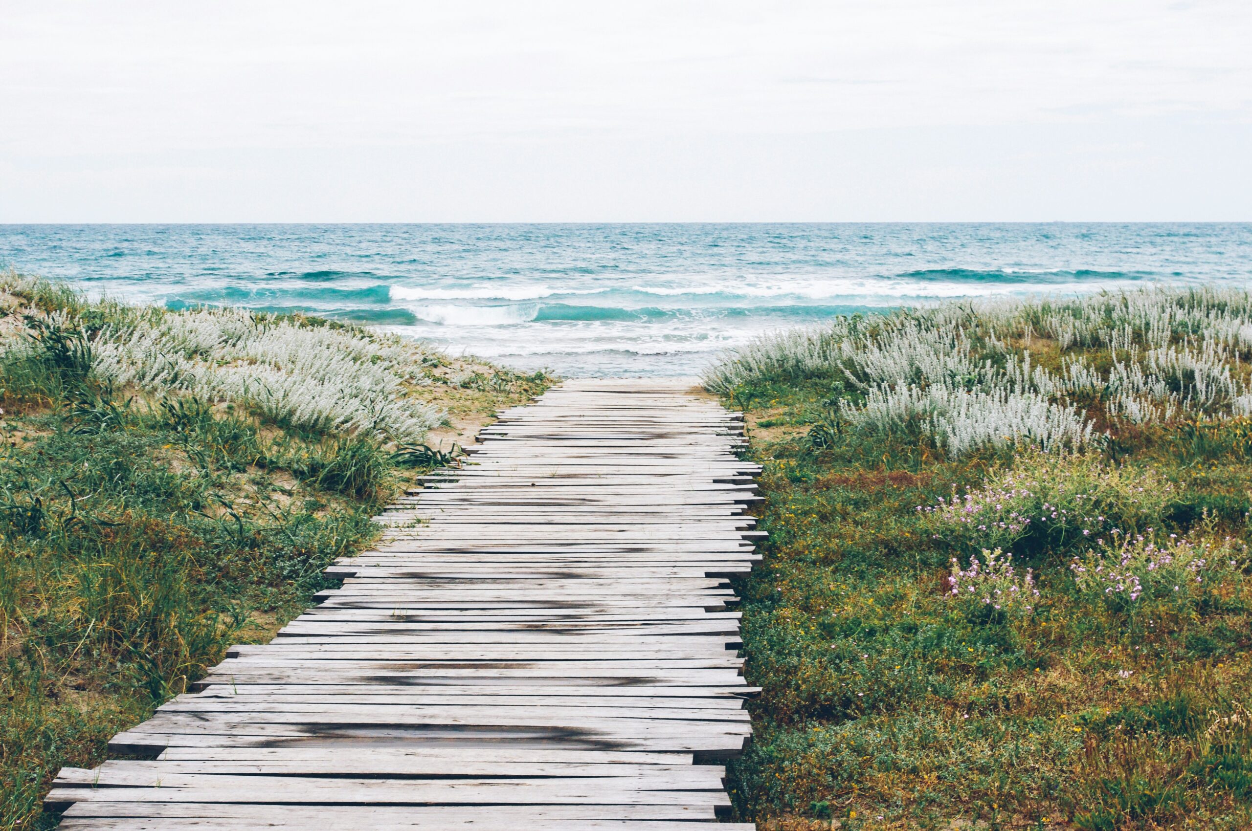 aleksandra-boguslawska-MS7KD9Ti7FQ-unsplash - Bridging Divorce Solutions Wooden boardwalk between grass and sand hills leading to blue ocean